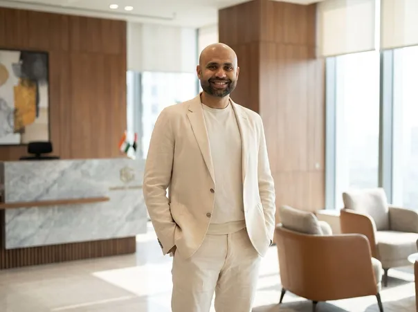 Rahul Gupta standing in a modern office reception area, wearing a cream suit.